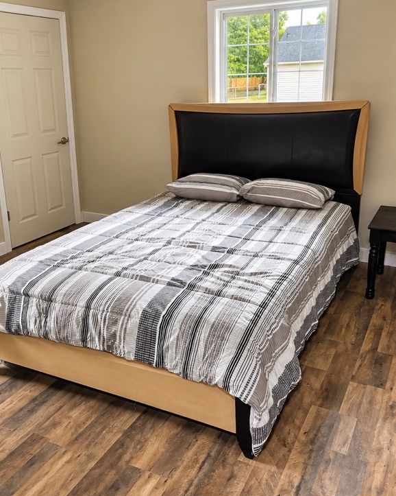 Bedroom with a full bed, dark headboard and window