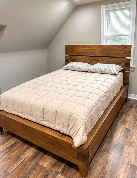 Bedroom with a wooden bed frame and cream bedding