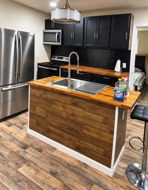 Kitchen with a wood-topped island, sink and stainless steel refrigerator