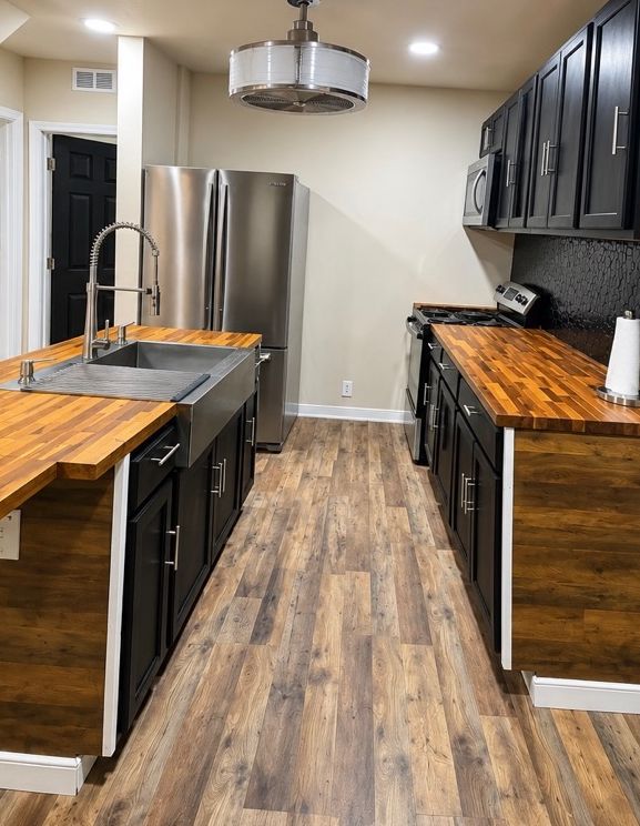 Galley view of the kitchen with dark cabinets and wood counters