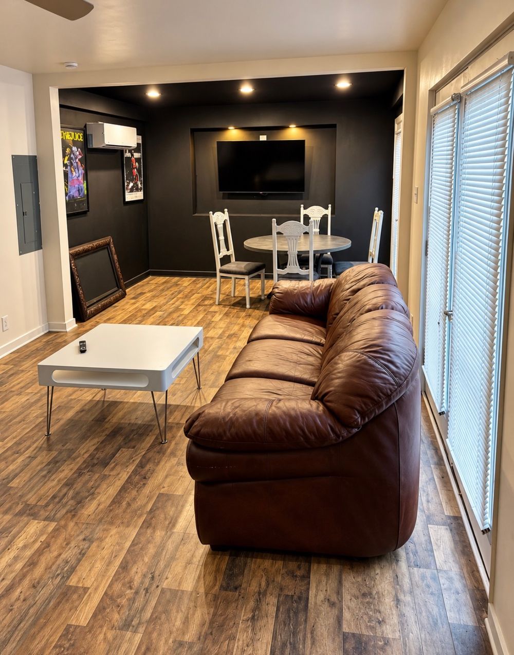 Living room with a leather sofa, coffee table, dining table and wall-mounted television
